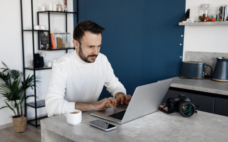 bel-homme-utilisant-ordinateur-portable-maison-dans-cuisine