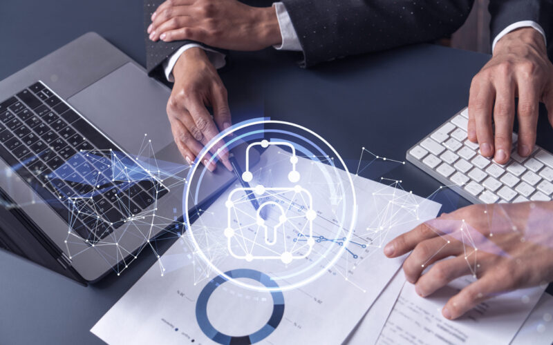 Two businesspeople man and woman working on the project to protect cyber security of international company. Padlock Hologram icons over the table with documents. Formal wear. Workspace.