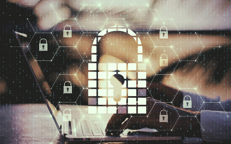 Side view of hands using laptop and smartphone with creative glowing digital padlock interface on blurry background with icons. Safety and protection concept. Multiexposure