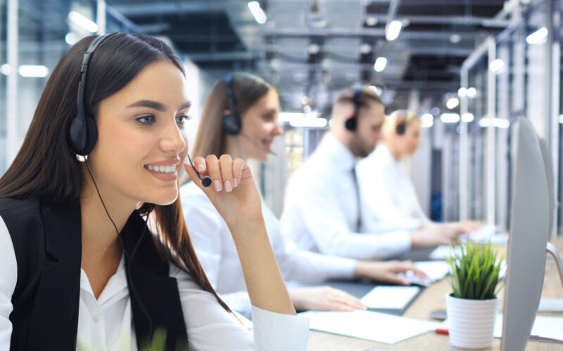 Portrait of call center worker accompanied by his team. Smiling customer support operator at work